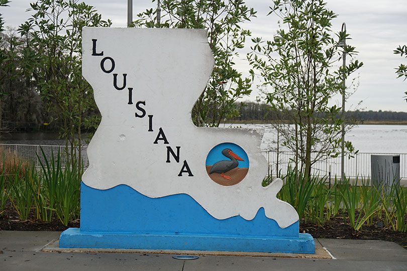 Concrete block in the shape of Louisiana with the state name on it and a pelican.